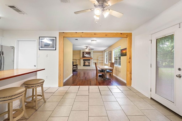 110 Willow Dr, Covington, LA 70433 - dining space featuring ceiling fan, a brick fireplace, baseboards, light tile patterned flooring, and ornamental molding