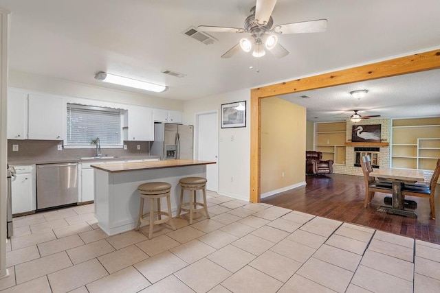 110 Willow Dr, Covington, LA 70433 - kitchen with stainless steel appliances, ceiling fan, a sink, white cabinetry, and a kitchen island