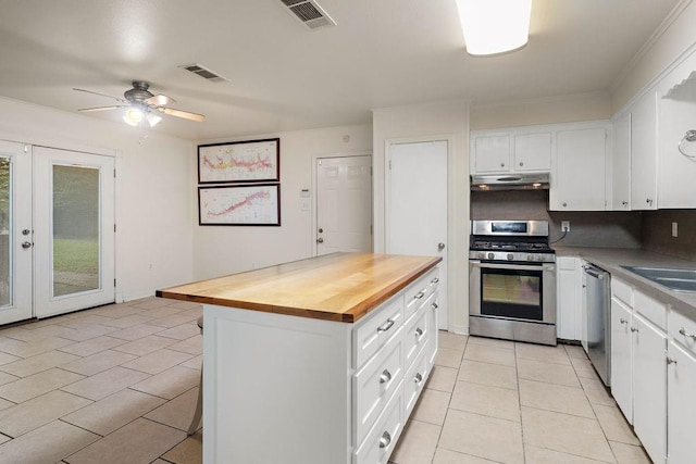 110 Willow Dr, Covington, LA 70433 - kitchen featuring stainless steel appliances, butcher block counters, under cabinet range hood, light tile patterned floors, and white cabinets