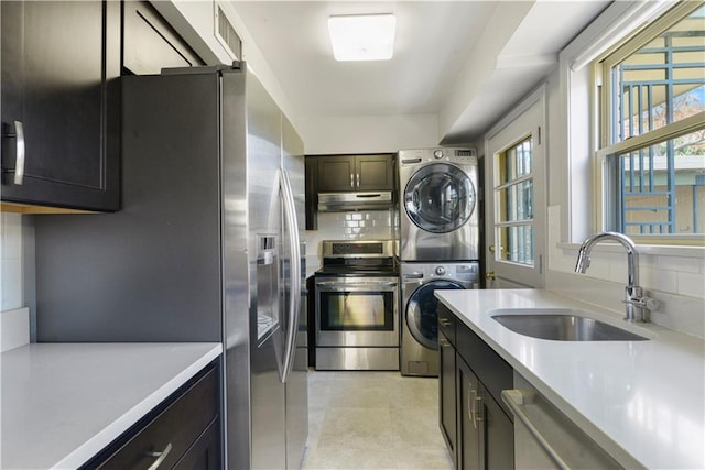 7356 Cameo St, New Orleans, LA 70124 - kitchen with appliances with stainless steel finishes, a sink, stacked washer / dryer, under cabinet range hood, and light countertops