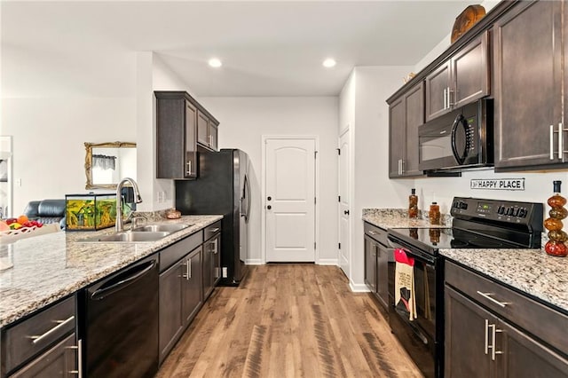 23406 Ruger Dr, Denham Springs, LA 70726 - kitchen with black appliances, a sink, dark brown cabinetry, light wood finished floors, and light stone countertops