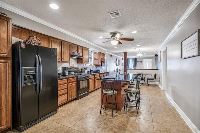 4633 Glendale St, Metairie, LA 70006 - kitchen with black appliances, under cabinet range hood, dark countertops, a kitchen breakfast bar, and crown molding