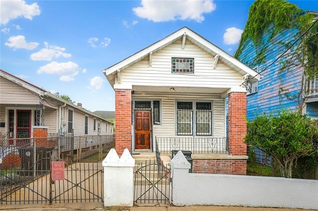 925 N Prieur St, New Orleans, LA 70116 - shotgun-style home featuring a porch, a gate, a fenced front yard, and brick siding