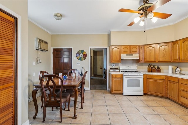 925 N Prieur St, New Orleans, LA 70116 - kitchen featuring white gas stove, under cabinet range hood, a wall mounted AC, crown molding, and ceiling fan