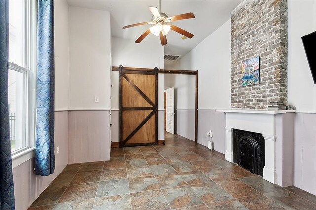 324 Angela St, Arabi, LA 70032 - unfurnished living room featuring ceiling fan, healthy amount of natural light, stone finish floors, a barn door, and vaulted ceiling