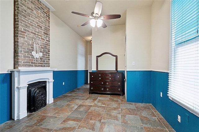 324 Angela St, Arabi, LA 70032 - unfurnished living room featuring stone finish flooring, a ceiling fan, a fireplace, and a wainscoted wall