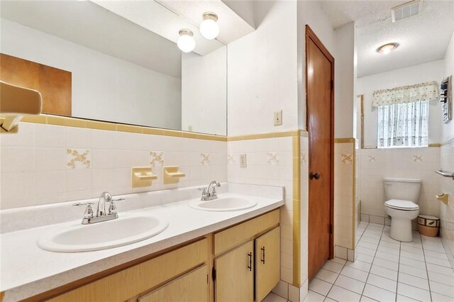 1500 Hudson St, Kenner, LA 70062 - bathroom featuring tile walls, tile patterned floors, double vanity, a wainscoted wall, and toilet