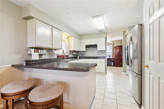 7045 River Rd, Waggaman, LA 70094 - kitchen featuring stainless steel fridge, a peninsula, a textured ceiling, light tile patterned floors, and a sink