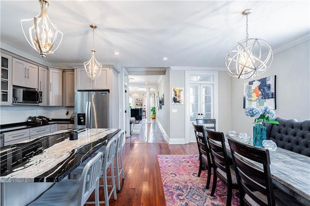 2134 Harmony St, New Orleans, LA 70115 - kitchen with stainless steel appliances, a chandelier, crown molding, gray cabinets, and a breakfast bar area