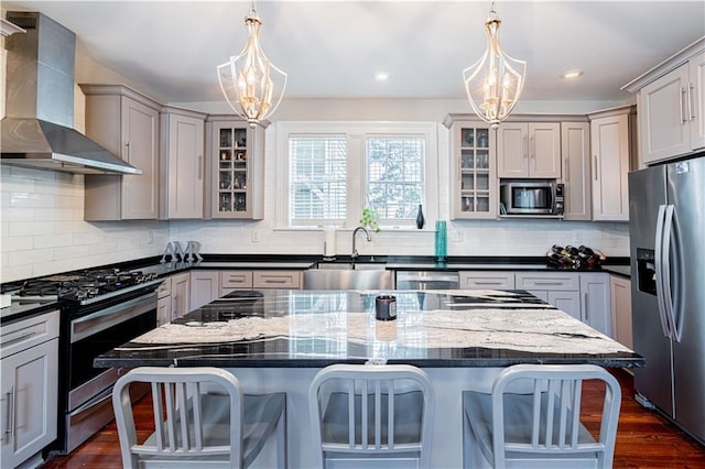 2134 Harmony St, New Orleans, LA 70115 - kitchen with stainless steel appliances, wall chimney range hood, a sink, a chandelier, and a kitchen breakfast bar
