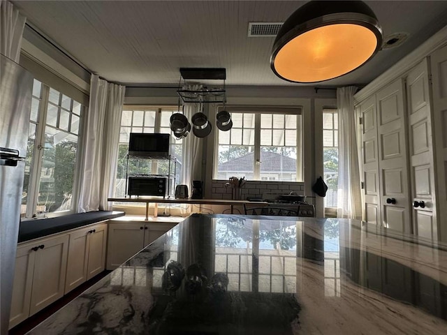 1228 Pine St, New Orleans, LA 70118 - kitchen featuring healthy amount of natural light, a large fireplace, and dark stone countertops