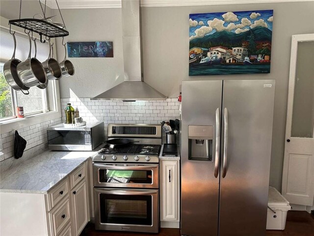 1228 Pine St, New Orleans, LA 70118 - kitchen with appliances with stainless steel finishes, wall chimney range hood, backsplash, cream cabinets, and crown molding