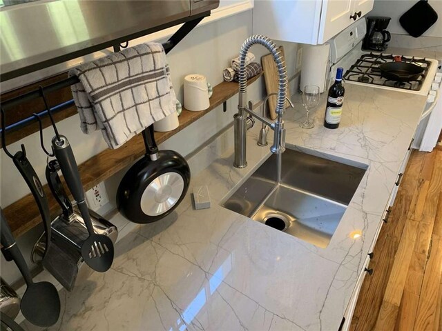 1228 Pine St, New Orleans, LA 70118 - kitchen view of a sink, white cabinetry, and light stone countertops