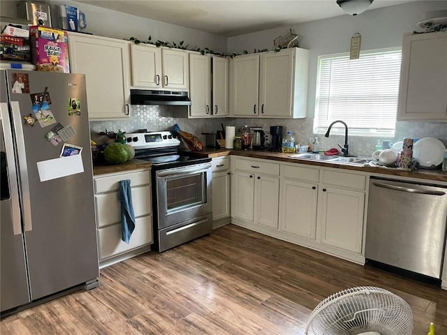 1127 Cousin St, Slidell, LA 70458 - kitchen with stainless steel appliances, under cabinet range hood, a sink, backsplash, and wood finished floors