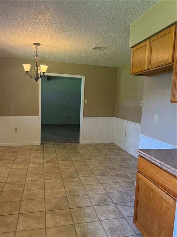106 Leonell Cir, Slidell, LA 70458 - unfurnished dining area with wainscoting, a chandelier, and a textured ceiling