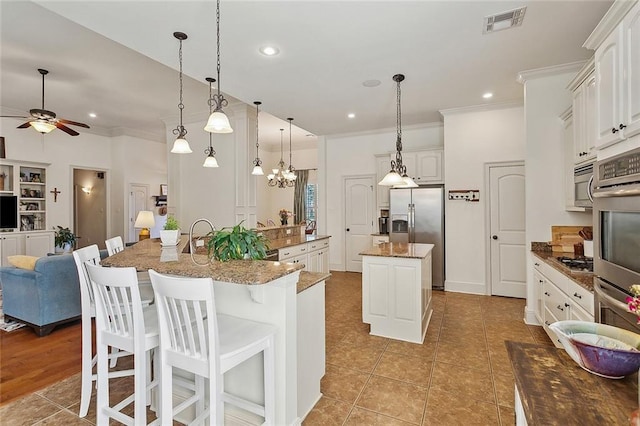 229 Pine Crest Dr, Madisonville, LA 70447 - kitchen featuring an island with sink, appliances with stainless steel finishes, ornamental molding, a ceiling fan, and recessed lighting