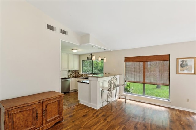 71152 Cutter Pl, Abita Springs, LA 70420 - kitchen with a peninsula, vaulted ceiling, stainless steel dishwasher, dark wood-style flooring, and decorative backsplash