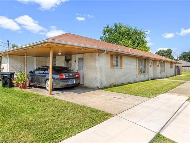 340103 Frenchmen St, New Orleans, LA 70122 - view of front of home featuring driveway, brick siding, an attached carport, and a front yard