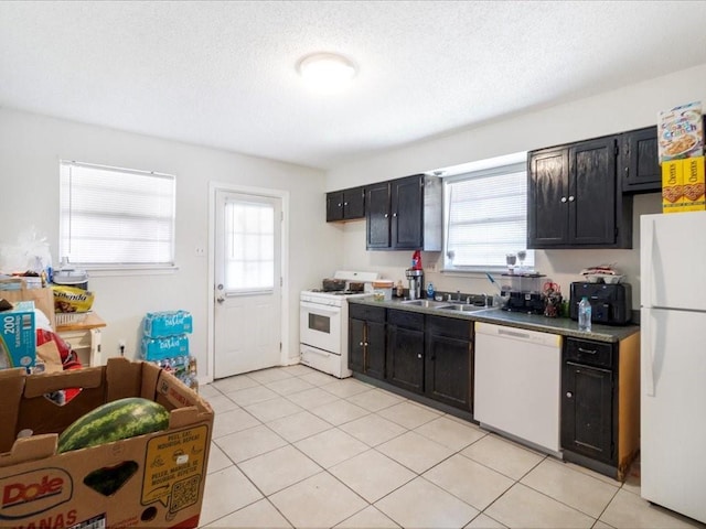 340103 Frenchmen St, New Orleans, LA 70122 - kitchen featuring white appliances, dark cabinetry, light tile patterned floors, and a sink