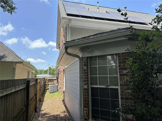 108 Riverbirch Dr, Lafayette, LA 70508 - view of side of property featuring central AC unit, solar panels, brick siding, and roof with shingles
