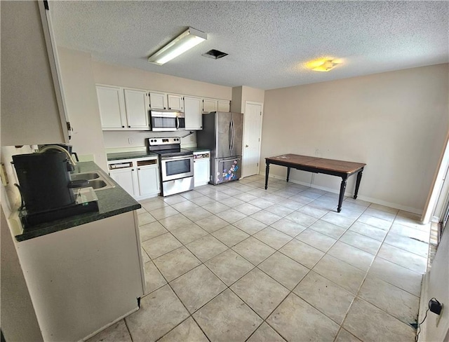 2724 Marisha Ct, Marrero, LA 70072 - kitchen with appliances with stainless steel finishes, a sink, white cabinetry, light tile patterned floors, and dark countertops