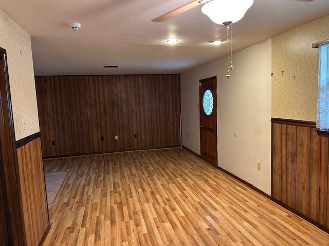 523 Beverly Garden Dr, Metairie, LA 70001 - spare room with light wood finished floors, wood walls, and a ceiling fan