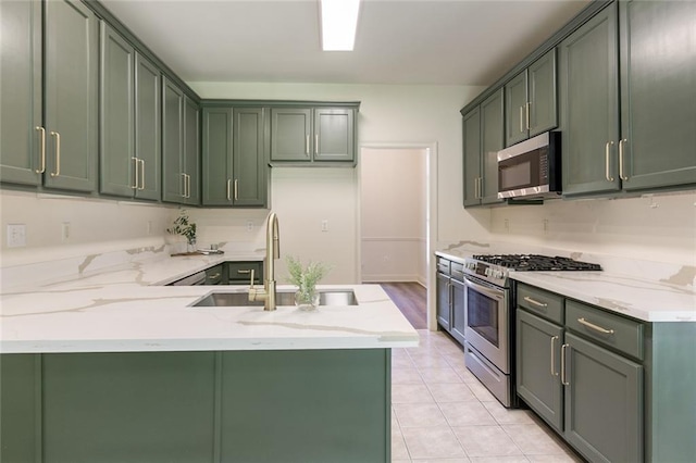 2308 Crossing Ct, Mandeville, LA 70448 - kitchen featuring stainless steel appliances, a peninsula, a sink, light stone countertops, and green cabinetry