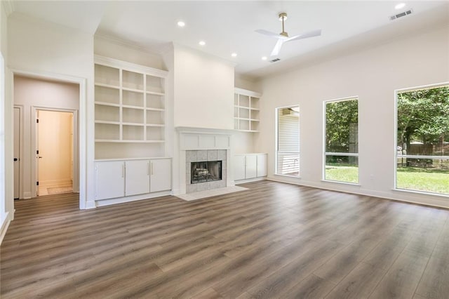 2308 Crossing Ct, Mandeville, LA 70448 - unfurnished living room with ornamental molding, a tiled fireplace, wood finished floors, ceiling fan, and built in features