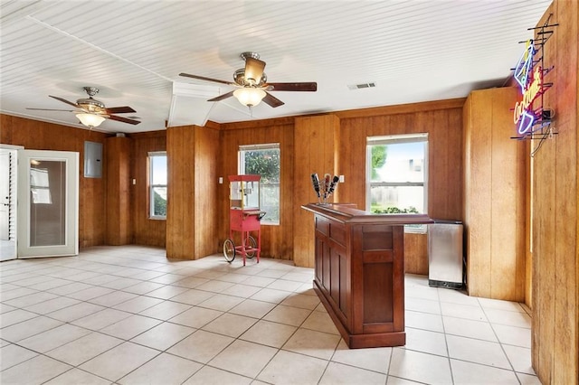 4321 San Remo Rd, New Orleans, LA 70129 - kitchen featuring brown cabinets, wooden walls, a ceiling fan, electric panel, and light tile patterned floors