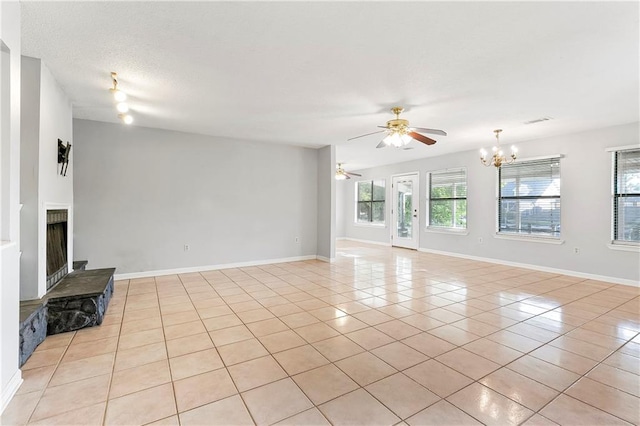 206 Chubasco Ln, Slidell, LA 70458 - unfurnished living room featuring light tile patterned floors, a chandelier, a ceiling fan, a fireplace with raised hearth, and baseboards