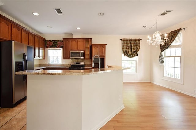 105 Norton Ave, Arabi, LA 70032 - kitchen with appliances with stainless steel finishes, a chandelier, a kitchen island with sink, light stone counters, and ornamental molding