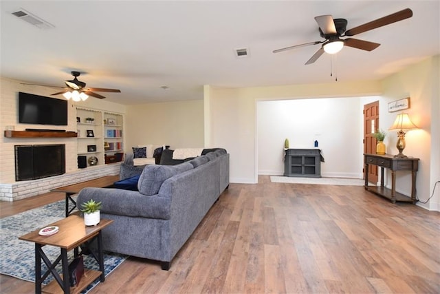 206 Loop Dr, Slidell, LA 70458 - living room featuring ceiling fan, wood finished floors, a brick fireplace, baseboards, and built in shelves