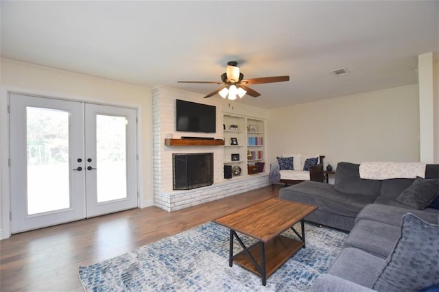 206 Loop Dr, Slidell, LA 70458 - living room featuring a ceiling fan, wood finished floors, french doors, built in shelves, and a fireplace