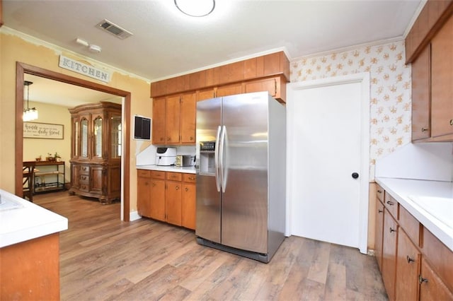 206 Loop Dr, Slidell, LA 70458 - kitchen featuring stainless steel fridge with ice dispenser, crown molding, brown cabinetry, light countertops, and light wood-style floors