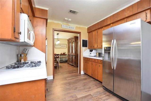 206 Loop Dr, Slidell, LA 70458 - kitchen with white appliances, brown cabinets, light countertops, light wood-style flooring, and crown molding