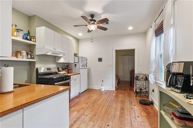 182527 Cambronne St, New Orleans, LA 70118 - kitchen with under cabinet range hood, stainless steel gas stove, butcher block countertops, freestanding refrigerator, and recessed lighting