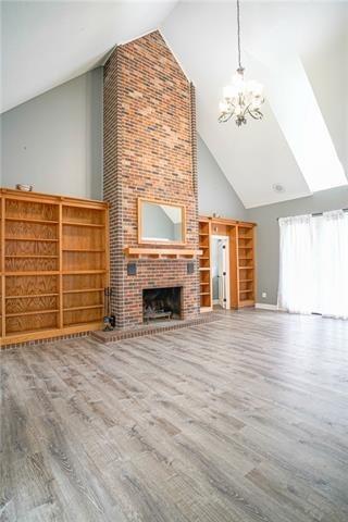 115 Devereux Dr, Slidell, LA 70461 - unfurnished living room with high vaulted ceiling, a chandelier, wood finished floors, a fireplace, and baseboards