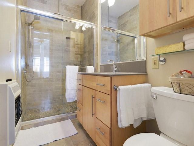 39294 Broadway St, New Orleans, LA 70118 - bathroom featuring toilet, heating unit, vanity, a shower stall, and tile patterned flooring