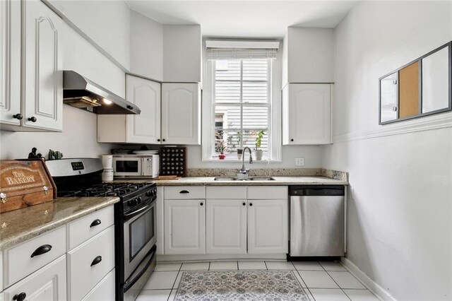 39294 Broadway St, New Orleans, LA 70118 - kitchen featuring appliances with stainless steel finishes, wall chimney exhaust hood, a sink, white cabinetry, and light tile patterned floors