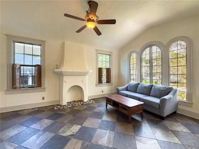 2508 Joseph St, New Orleans, LA 70115 - living room with lofted ceiling, stone tile flooring, baseboards, ceiling fan, and a large fireplace