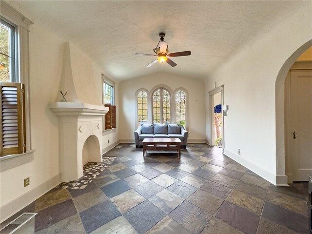 2508 Joseph St, New Orleans, LA 70115 - living room with ceiling fan, arched walkways, stone tile floors, baseboards, and lofted ceiling