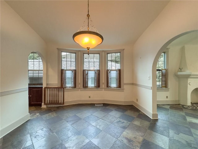 2508 Joseph St, New Orleans, LA 70115 - unfurnished dining area featuring baseboards, arched walkways, and stone tile floors