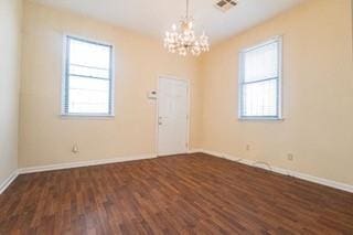 181113 Aubry St, New Orleans, LA 70116 - spare room with healthy amount of natural light, a chandelier, dark wood-type flooring, and baseboards
