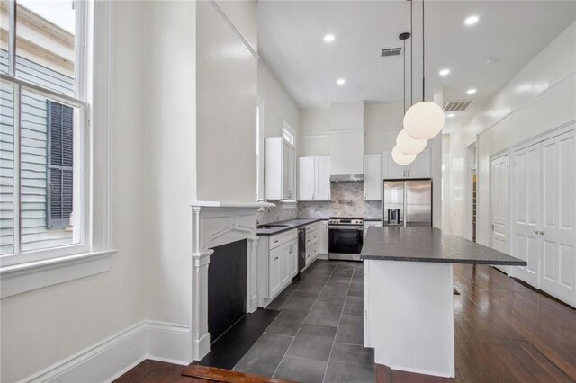 4628 Cleveland Ave, New Orleans, LA 70119 - kitchen featuring appliances with stainless steel finishes, dark countertops, a kitchen island, backsplash, and white cabinetry