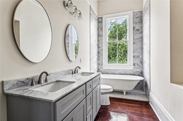 4628 Cleveland Ave, New Orleans, LA 70119 - full bath featuring wood finished floors, double vanity, a soaking tub, and toilet