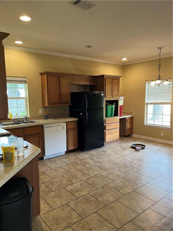 42984 River Birch Ln, Franklinton, LA 70438 - kitchen with freestanding refrigerator, dishwasher, light countertops, ornamental molding, and brown cabinetry