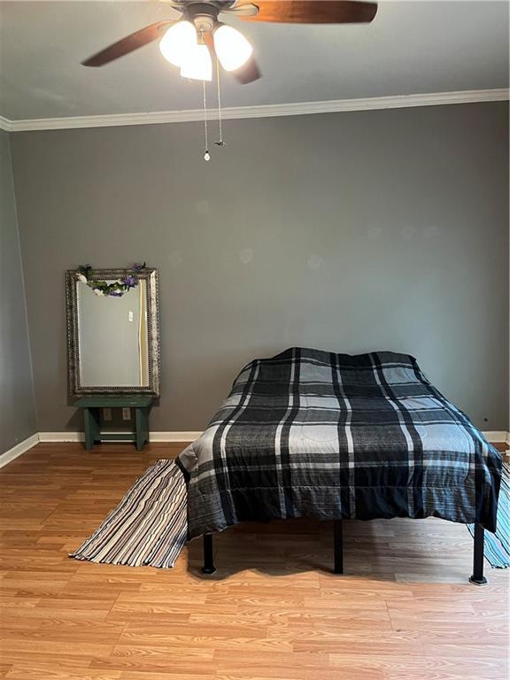 42984 River Birch Ln, Franklinton, LA 70438 - bedroom with light wood-type flooring, baseboards, ornamental molding, and a ceiling fan