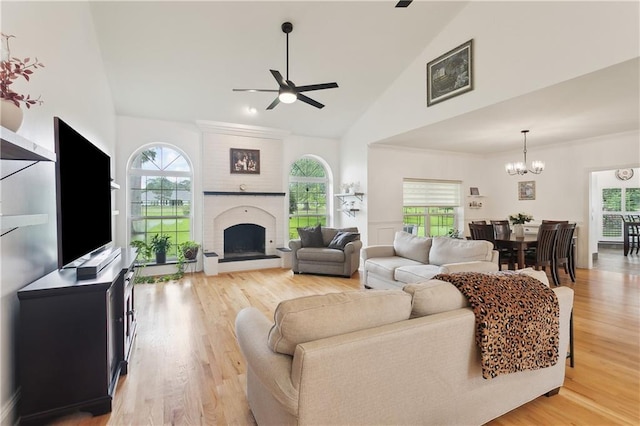 733 Plantation Dr, Abita Springs, LA 70420 - living room featuring a ceiling fan, high vaulted ceiling, a chandelier, a fireplace, and light wood-type flooring