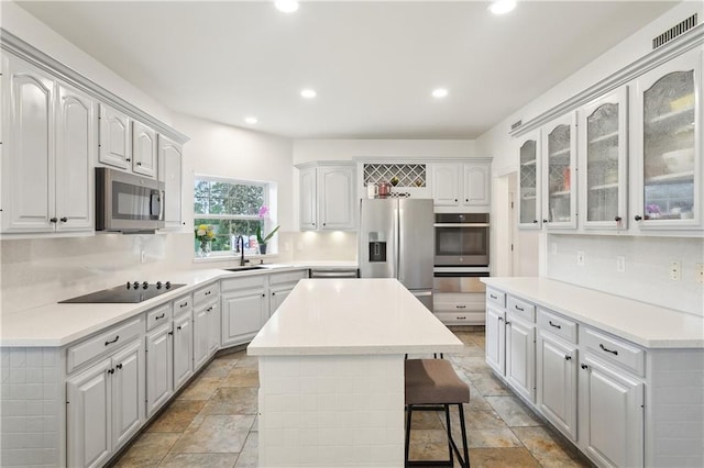 733 Plantation Dr, Abita Springs, LA 70420 - kitchen with appliances with stainless steel finishes, a sink, a center island, recessed lighting, and glass insert cabinets