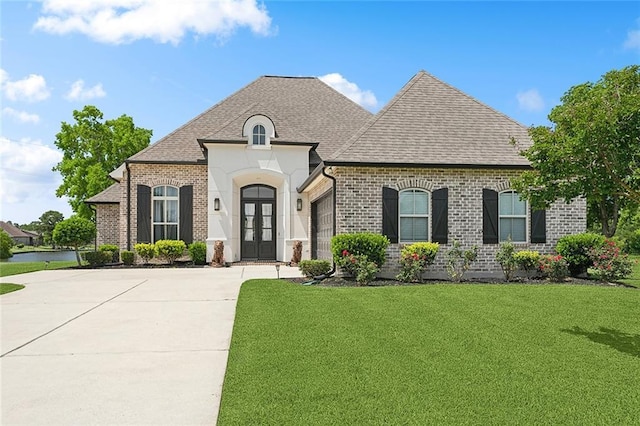 317 E Augusta Ln, Slidell, LA 70458 - french country inspired facade featuring a garage, concrete driveway, brick siding, a front lawn, and roof with shingles